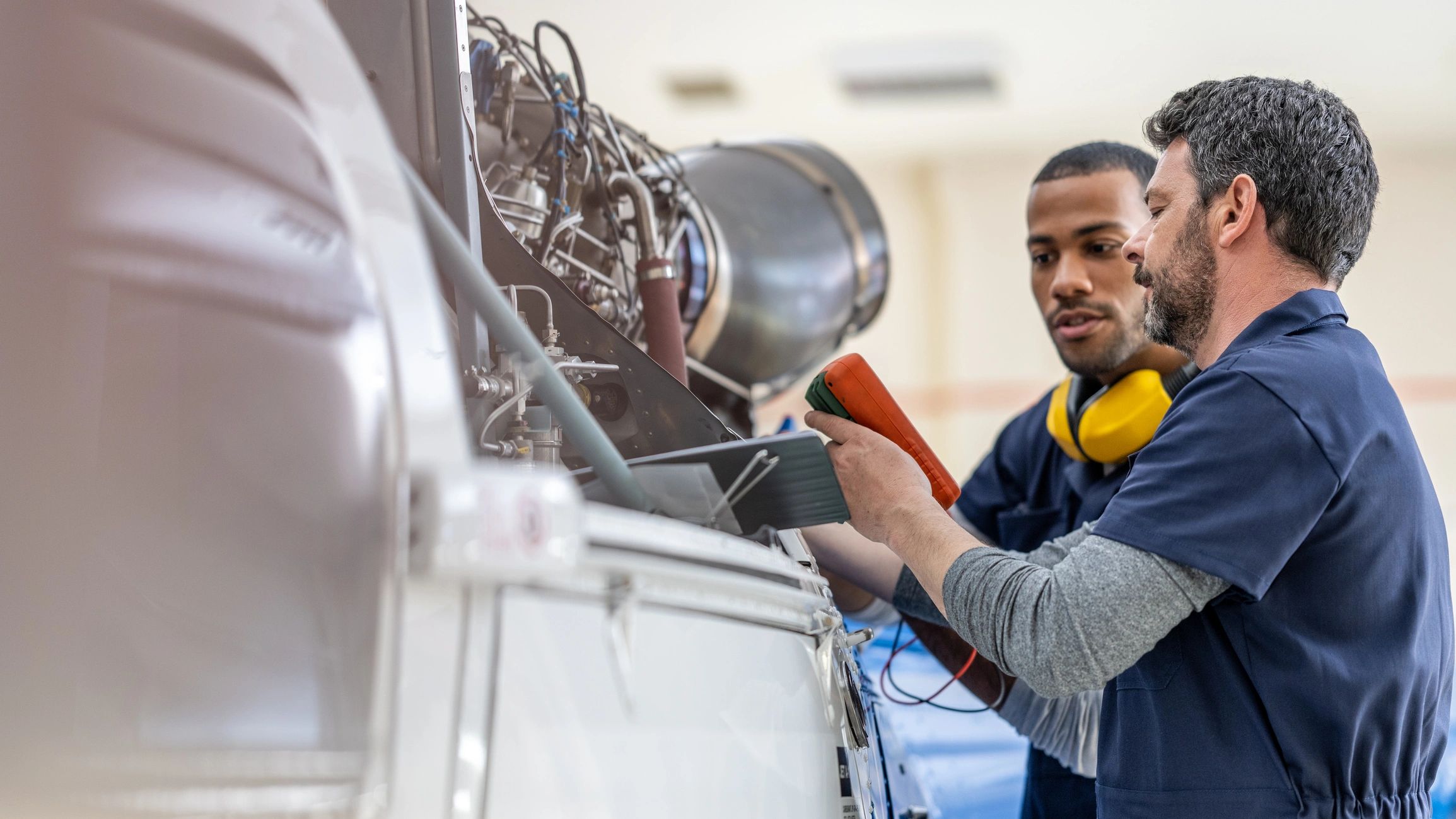 Aircraft professionals examining an engine in a hangar