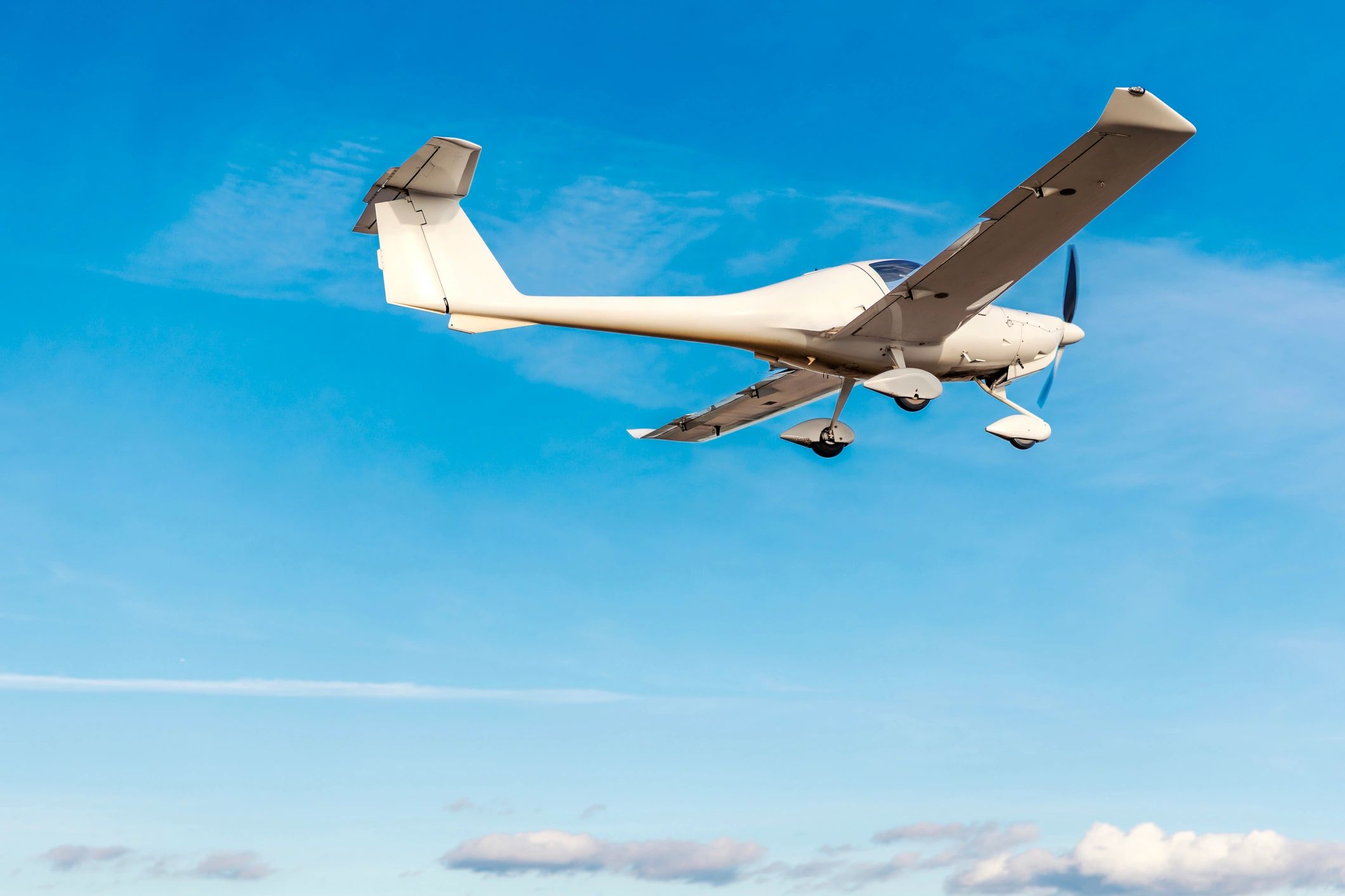 Small airplane flying with propeller spinning against blue sky
